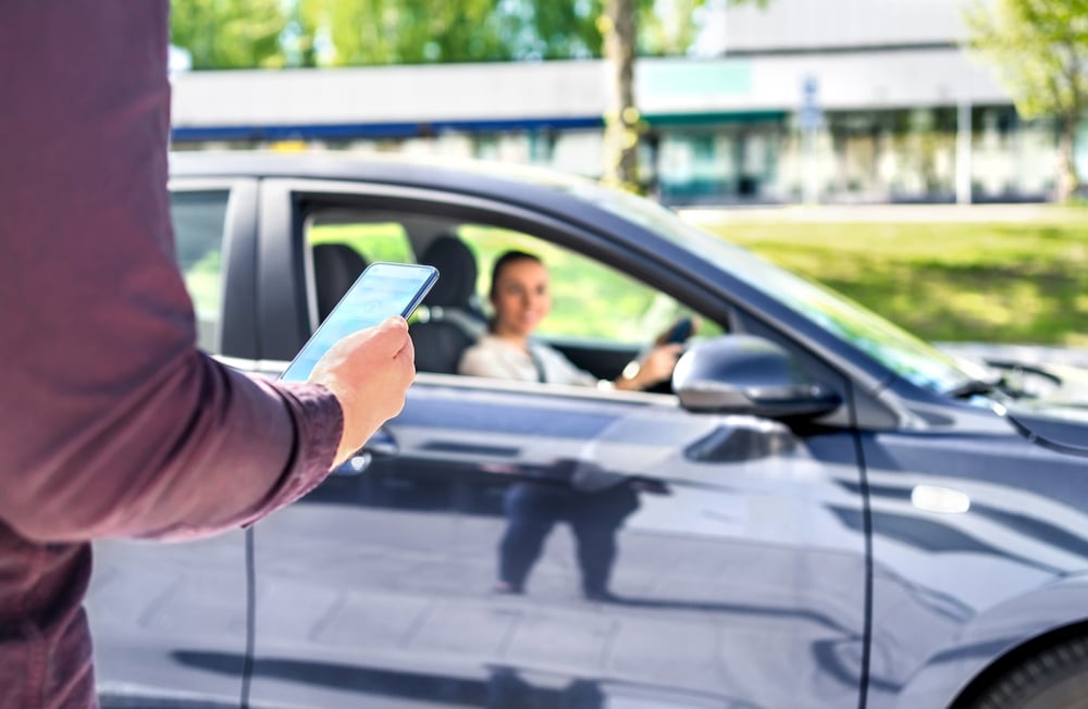 muškarac s mobitelom prilazi ženi za volanom